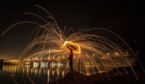 Man spinning wire wool at night