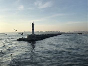 View of lighthouse by sea against sky