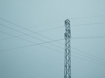 Low angle view of electricity pylon against clear sky