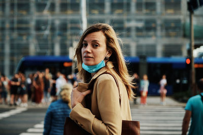 Woman wearing protective mask in the city. woman in coat walks at city street during covid-19