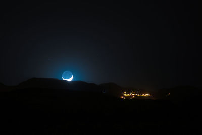 Scenic view of illuminated mountains against clear sky at night