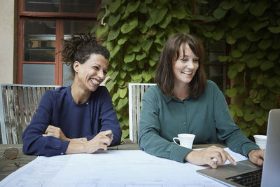 Female architect smiling while looking at laptop in backyard