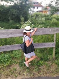Rear view of woman in hat standing against trees