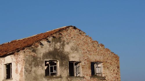 Low angle view of old building against clear blue sky