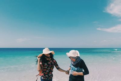 Full length of friends on beach against sky