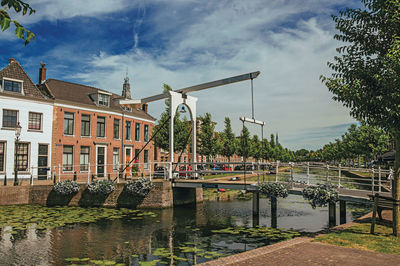 Buildings by river against sky in city