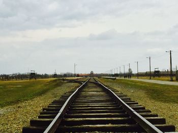 Surface level of railroad tracks on field against sky