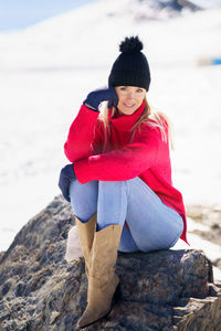 Woman sitting on rock at beach during winter