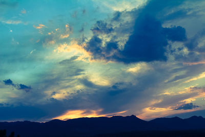 Low angle view of silhouette mountains against dramatic sky