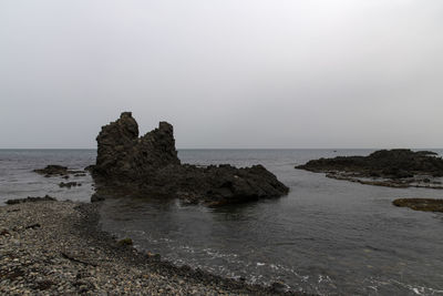 Scenic view of rocks on sea against clear sky