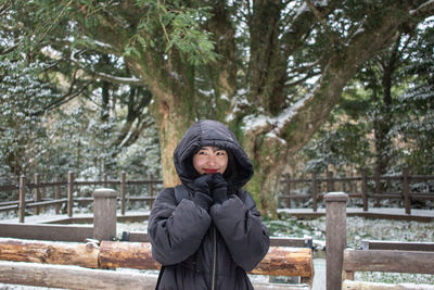 Portrait of young woman standing in park during winter