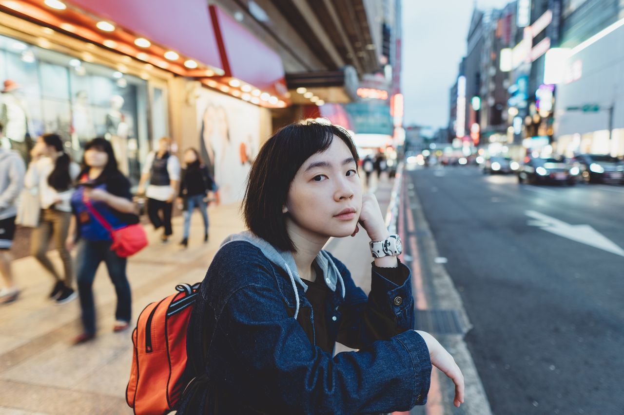 city, one person, lifestyles, real people, focus on foreground, architecture, street, leisure activity, incidental people, young adult, young women, road, transportation, portrait, women, casual clothing, city life, waist up, city street, beautiful woman, outdoors, hairstyle