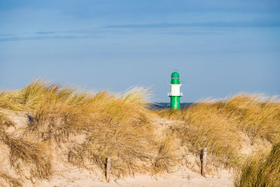 Lighthouse on beach against sky