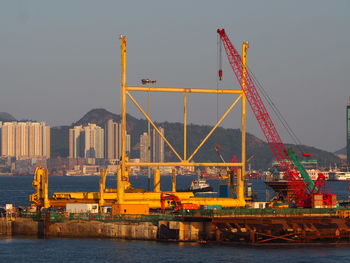 Cranes at commercial dock against clear sky