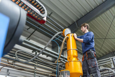 Worker filling production machine in plastics factory