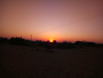 Scenic view of silhouette field against clear sky during sunset