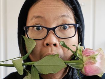 Close-up portrait of shocked woman with rose at home