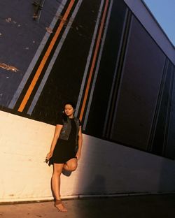 Young woman smoking cigarette while leaning on wall