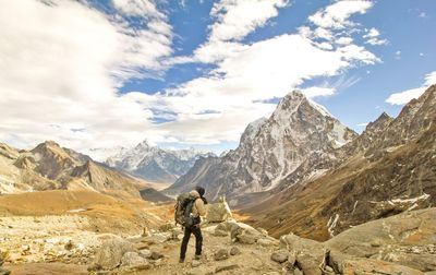 Rear view of man walking on mountain against sky