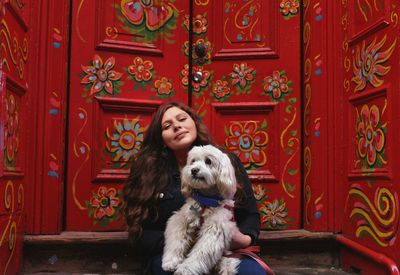 Portrait of man with dog sitting against door