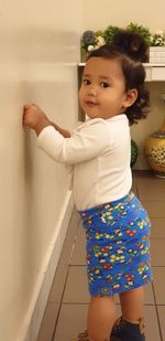 Portrait of cute girl standing against wall