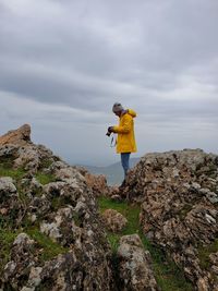 Man standing on rock against sky