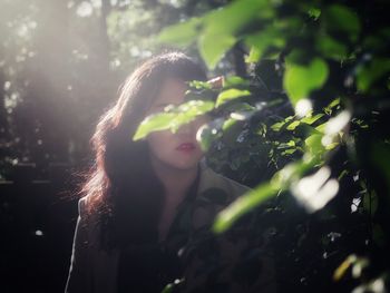 Portrait of young woman with plants in foreground