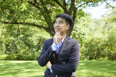 Smiling young woman looking away against trees
