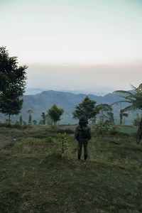 Rear view of man standing on field against sky