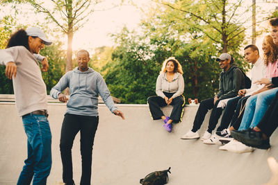 Friends looking at men dancing in skateboard park