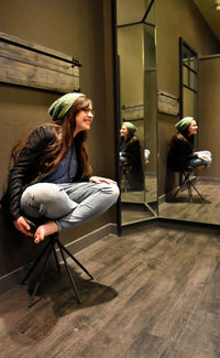 Happy young woman looking away while sitting on stool