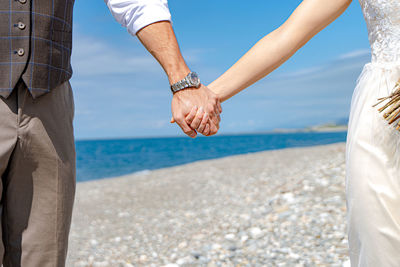 Midsection of man holding hands at beach