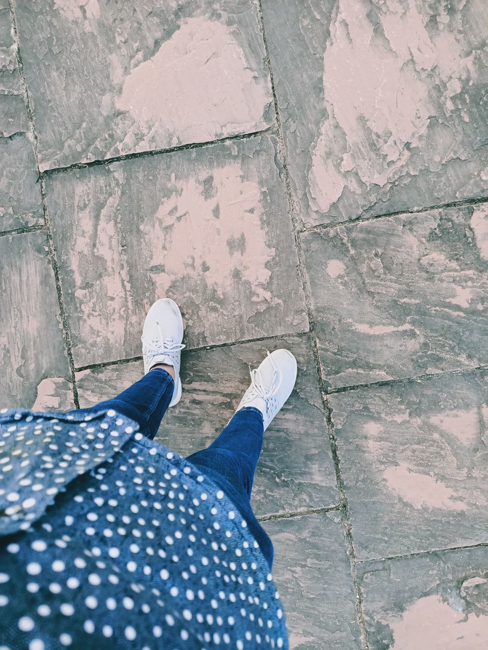 LOW SECTION OF PERSON STANDING ON COBBLESTONE FOOTPATH