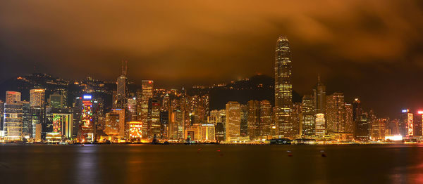 Illuminated modern buildings in city against sky at night