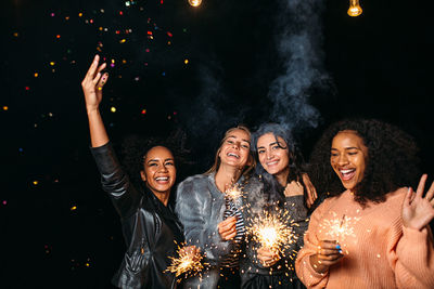 Portrait of woman holding firework display at night