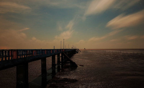 Pier over sea against sky during sunset
