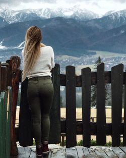 Rear view of woman standing by railing against mountains