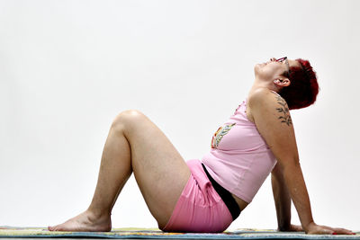 Woman sitting against pink background