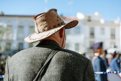 Rear view of man wearing hat against city