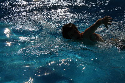 High angle view of man swimming in sea on sunny day