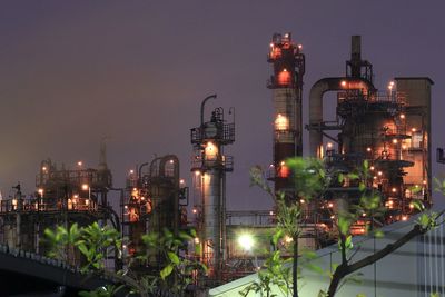 Illuminated factory against sky at night