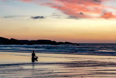 Silhouette man looking at sea against sky during sunset