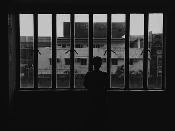 Rear view of silhouette man standing by window