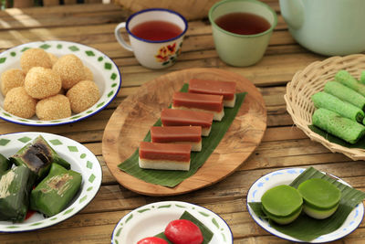 Various kue basah or indonesia jajan pasar on bamboo table. served wiith tea