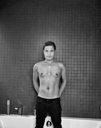Portrait of shirtless man standing against wall