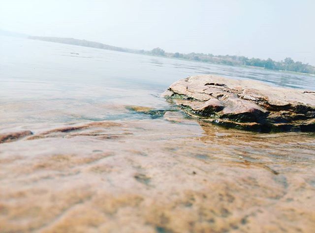 water, sea, tranquil scene, tranquility, scenics, beach, beauty in nature, shore, nature, clear sky, rock - object, surface level, idyllic, sky, coastline, calm, outdoors, day, remote, non-urban scene