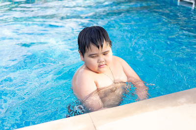 Full length of shirtless boy swimming in pool