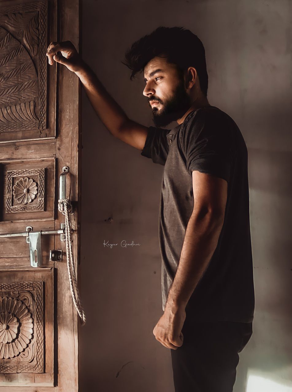 MAN LOOKING AWAY WHILE STANDING AGAINST WALL