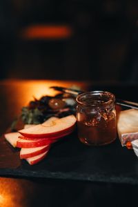 Composition of sliced cheese, a jar of honey and pieces of apples on a wooden stand