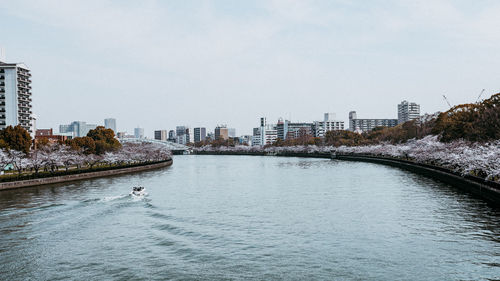 Buildings by river against sky